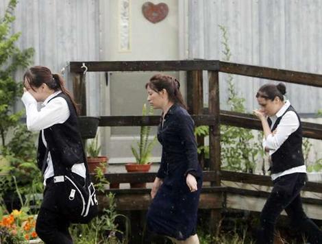 Stunned .hs.hs. three women walk through the rain to the
mobile home in Hudson Oaks, Texas, where the mother and her
children were found.